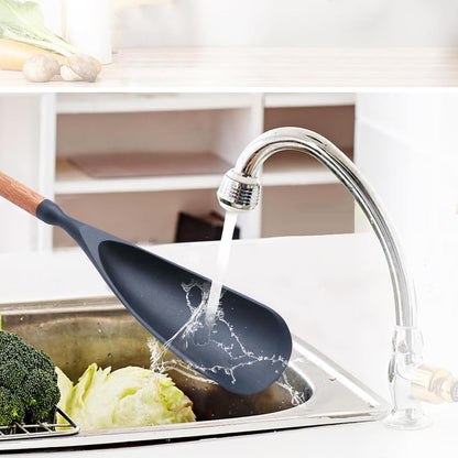 Black silicone cooking spoon rinsed under a kitchen faucet